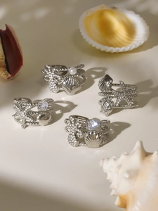 Detailed view of silver ocean-themed rings with starfish, shells, and sparkling zircons