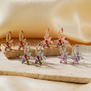 Elegant lotus flower zircon earrings in four metallic plating colors on stone background