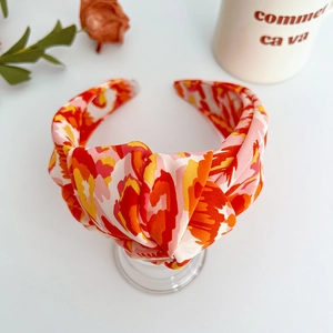 Close-up of knotted fabric headband with bright floral print on a white surface