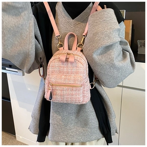 Detail of pink tweed mini backpack with leather straps and metallic hardware on a model