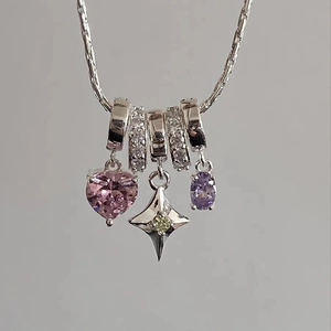 Detail of silver heart and star charms with colorful gemstones on a delicate necklace chain