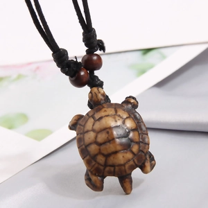 Close-up of brown resin turtle pendant with woven black rope and wooden beads decoration