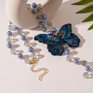 Detail of blue embroidered butterfly pendant with crystal beads on a vintage necklace