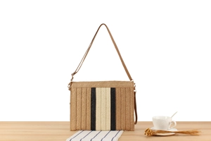 Detailed close-up of handmade woven paper straw shoulder bag with black and white stripes