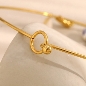 Macro detail of 18K gold-plated stainless steel ring and ball toggle closure