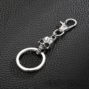 Detail of vintage skull keychain with lobster clasp on black leather texture background