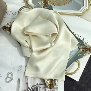 Detailed view of cream silk scarf texture on a gold tray with soft natural lighting