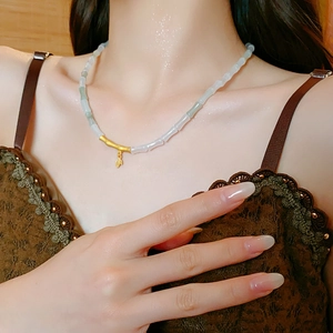 Detailed close-up of a bamboo style necklace with jade beads and a golden leaf pendant