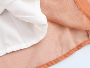 Detailed view of lightweight white lining and orange chiffon fabric hem with neat stitching