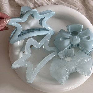 Artistic display of blue star and bow hair claws on a ceramic plate with linen backdrop