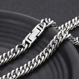 Close-up of a polished silver Cuban link chain necklace with a square buckle on a black disk