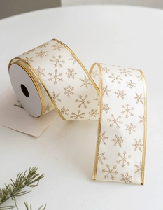 Detail of cream Christmas ribbon with gold snowflake patterns and wired gold edges