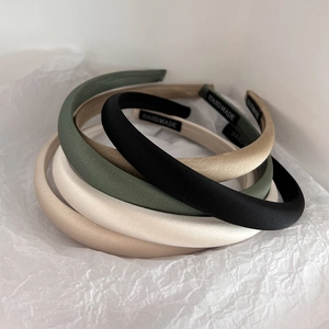 Minimalist satin headbands in black, green, and beige colors on white paper