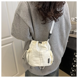 Close-up of white drawstring bucket bag showing textured fabric and fashion label