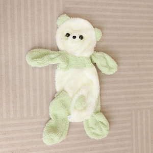 Détail macro de la housse d'ours en peluche vert et beige avec une texture douce et veloutée