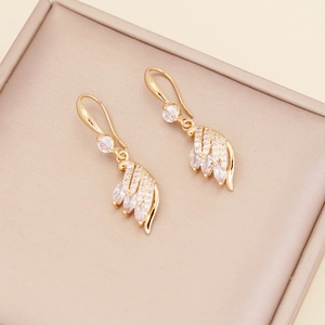 Elegant gold feather earrings with sparkling zircon crystals in a beige jewelry gift box