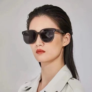 Modèle portant des lunettes de soleil oversize gris fumé avec verres noirs, décor minimaliste