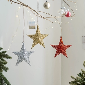 Glittering iron Christmas star ornaments in gold silver and red hanging on branches