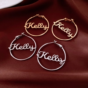 Detailed view of custom name earrings Kelly on luxurious red silk background