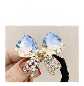 Detailed macro view of a crystal bow hair tie with iridescent rhinestones and gold base