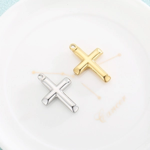 Polished gold and silver stainless steel cross pendants on a white ceramic plate