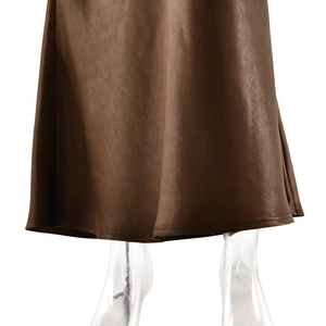 Detail of elegant brown satin dress hem with smooth draping and glossy silk texture
