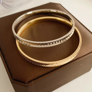 Macro view of gold and silver textured metal bangles with honeycomb pattern on a box