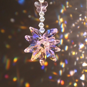 Macro detail of crystal snowflake pendant with butterfly charm and rainbow light refraction