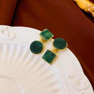 Retro geometric earrings with green marble resin on a white ceramic display plate