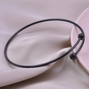 Detail of a minimalist black steel neck choker with matte beads on silk background