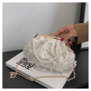 Detail of white satin evening clutch with pearl embellishments and gold metal frame