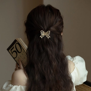 Elegant gold butterfly hair claw clip with pearls shown on model's hairstyle