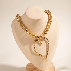 Close-up of golden multi-layer necklace featuring a large hollow heart pendant on a bead chain