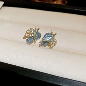 Elegant gold leaf earrings with blue enamel and marquise crystals in a jewelry box