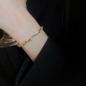 Detailed close-up of rainbow gemstone tennis bracelet with gold setting on model wrist
