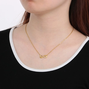Elegant gold infinity necklace with micro-pave diamonds worn by a model in a close-up view