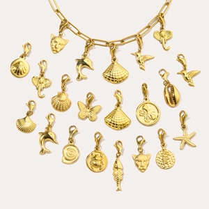 Detail of gold titanium steel pendants with lobster clasps featuring shells and dolphins