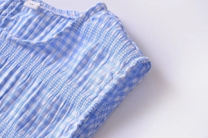 Detail of blue plaid top showing texture of breathable fabric and pleated shoulder seam
