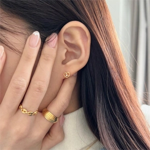 Close-up of elegant gold bow earrings and layered textured rings on a model