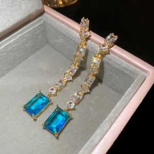 Close-up of gold dangle earrings with blue gemstones and zircons in a pink jewelry box