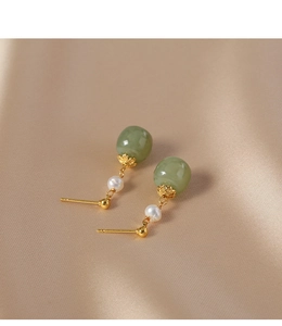 Detail of vintage gold earrings with green jade beads and white freshwater pearls