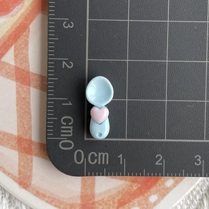 Macro detail of mini light blue resin spoon with pink heart on a scaled cutting mat
