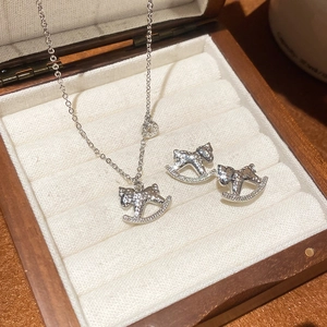 Détail d'un ensemble de bijoux cheval à bascule argenté avec cristaux dans une boîte en bois