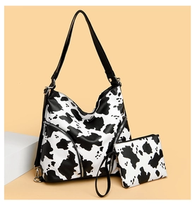Detail of black and white cow print tote bag and matching coin purse with silver hardware