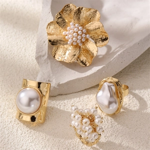 Detail of four vintage gold pearl rings featuring floral and baroque styles on stone
