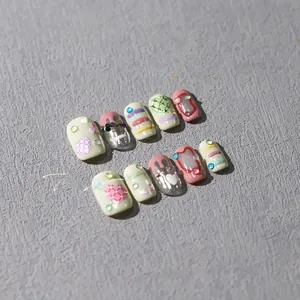 Detail of colorful macaron press-on nails with 3D embossed hearts and rhinestones