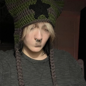 Detail of green and grey striped knit star cat ear hat with long braided tassels