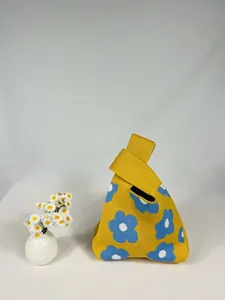 Detail of yellow knit bag with blue flower pattern and simple single handle strap