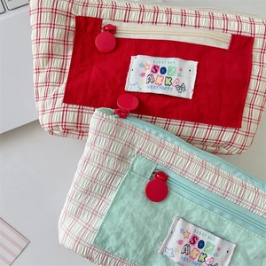 Detail of checkered fabric pencil case with smooth zipper and colorful cloth label