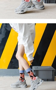 Detail of pink and black argyle lolita socks paired with grey chunky sneakers for women